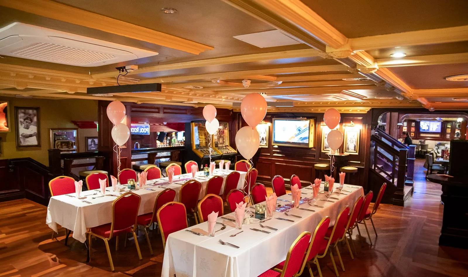 Long tables with red chairs and balloons set up for a party