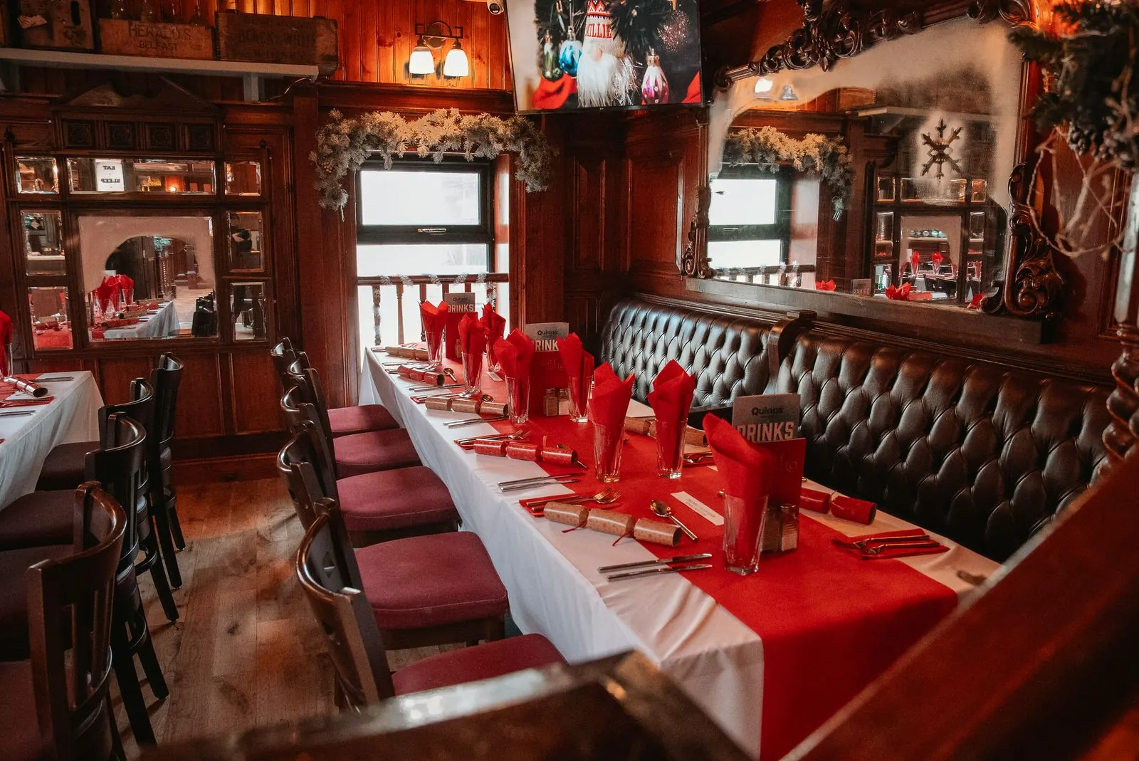 A long Christmas table beside the leather booth, with garlands in the windows